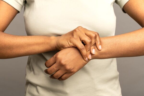 Black female arms massaging painful wrist suffering from weakness and tingling. Sport injury disease