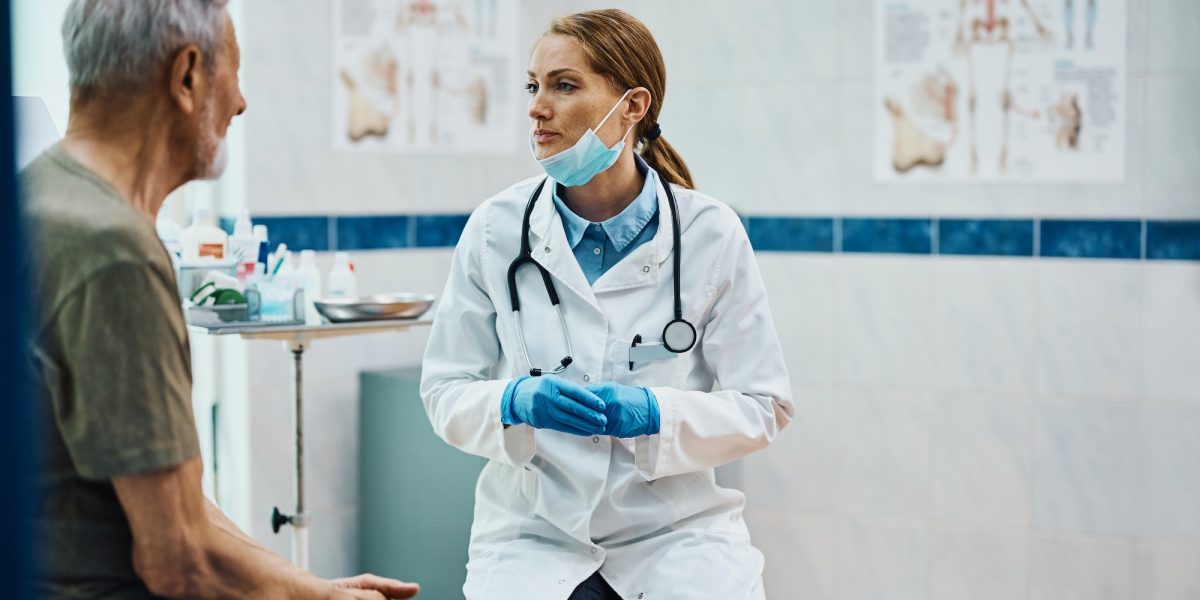 Female cardiologist communicating with mature patient at doctor's office.