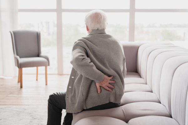 Patient at New Smyrna Wellness Center Physical Therapy Department touching his back, suffering from sciatica